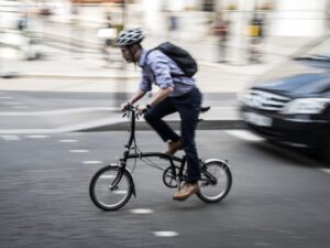 man on folding bike in city centre traffic