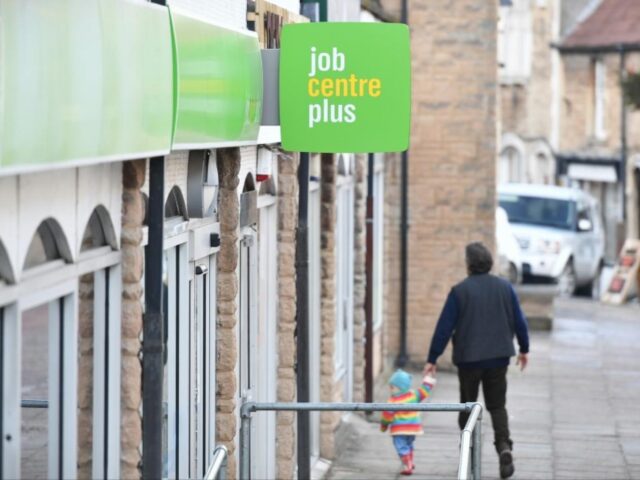 a man hand-in-hand with a child walking into a 'job centre plus'