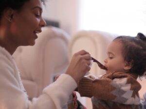 photo of woman feeding a child