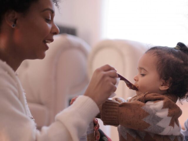 photo of woman feeding a child