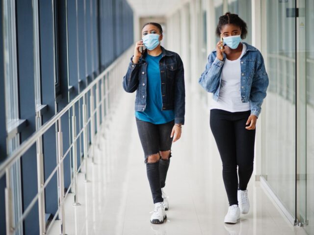 Photo of two women walking wearing masks