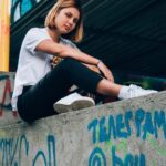 young woman sitting on wall