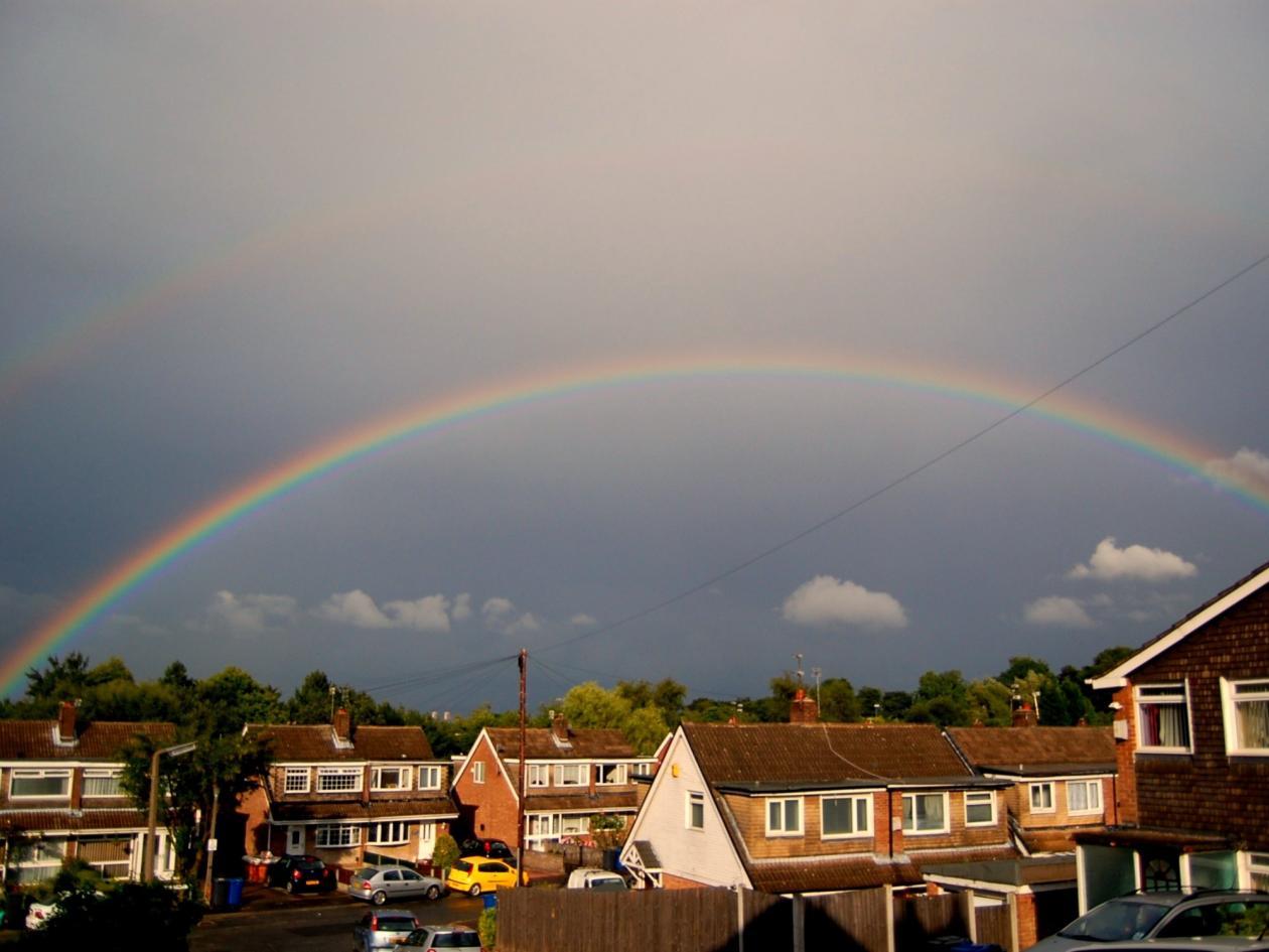 streets of houses with a rainbow in the sky above them