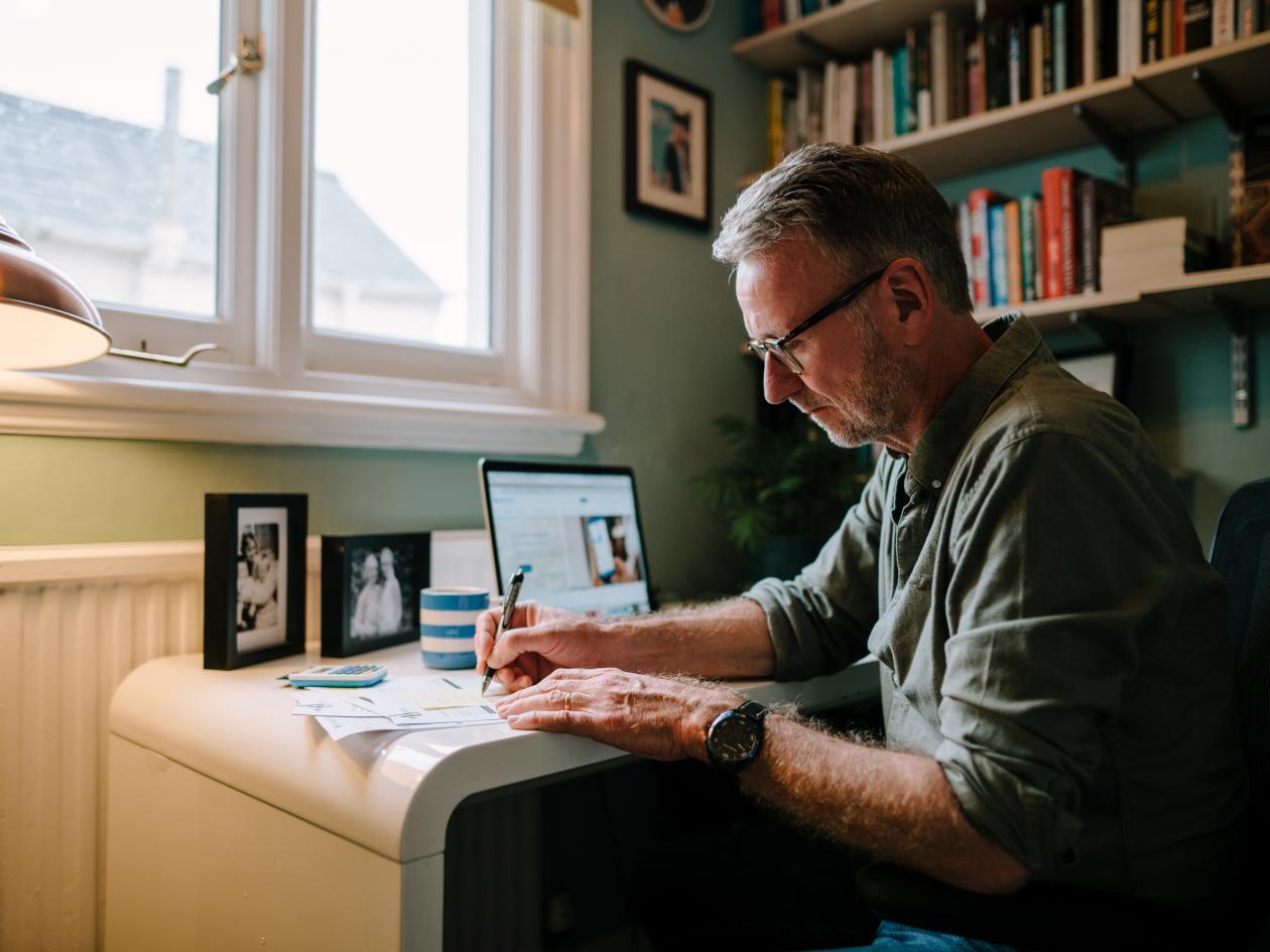 A middle aged man signs some paperwork