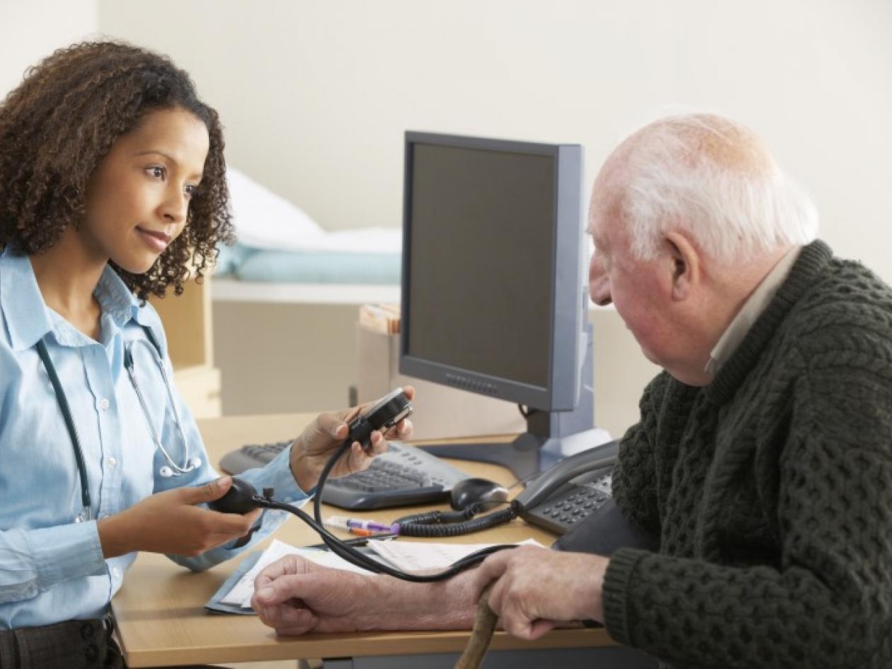 An older man has his blood pressure measured by a GP