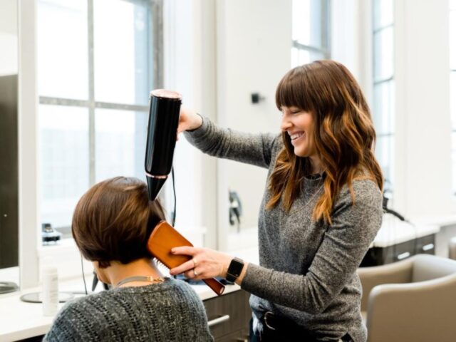 a hairdresser blow-drying a client's hair